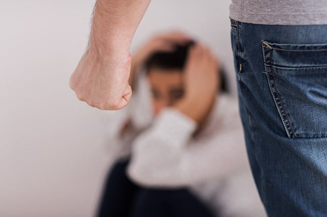 Young woman cowering from clenched fist