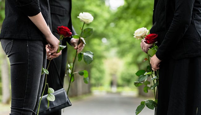 Group of friends exchanging roses at funeral