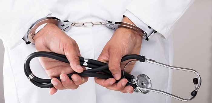 Doctor in handcuffs with stethoscope in hands