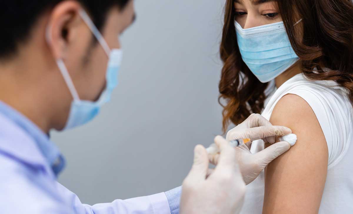 médico que le da al paciente una inyección de vacuna