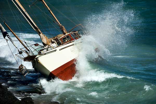 boat caught on rocks with waves splashing against it