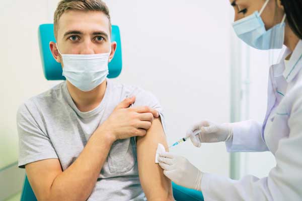 man holding up sleeve to receive vaccine injection