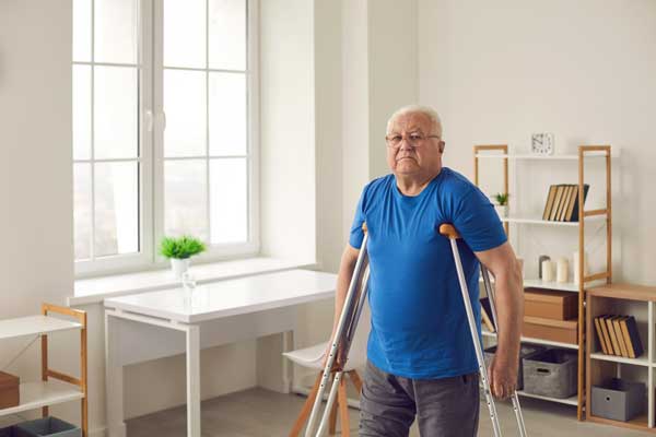 hombre con camisa azul de pie con apoyo de muletas