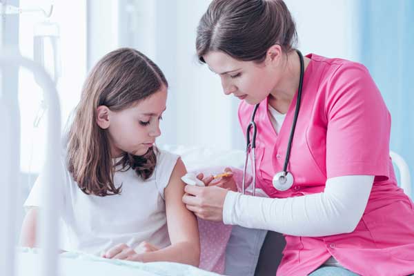 nurse in pink performing vaccine injection