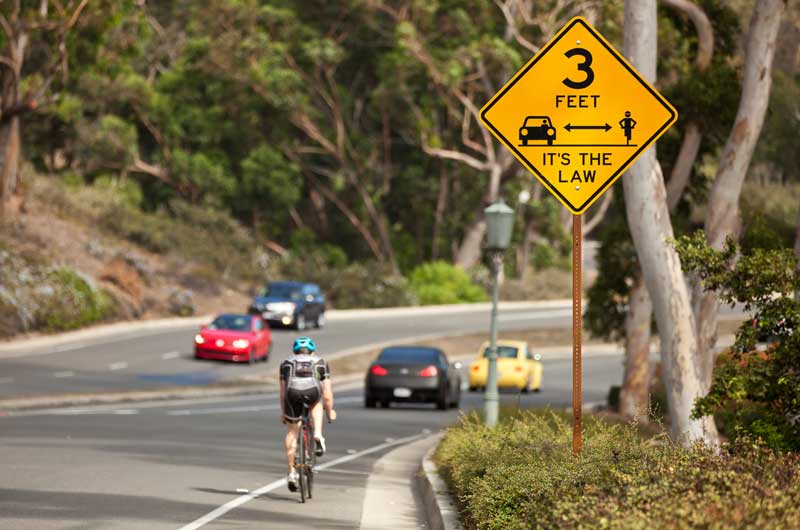 bicyclist riding past road sign