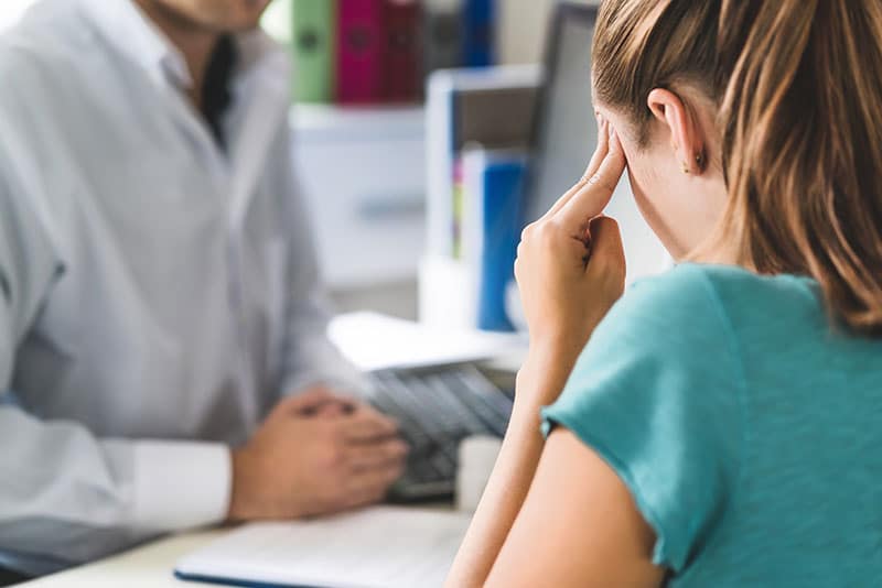 Mujer sosteniendo la cabeza con dolor después de una lesión en el tronco encefálico