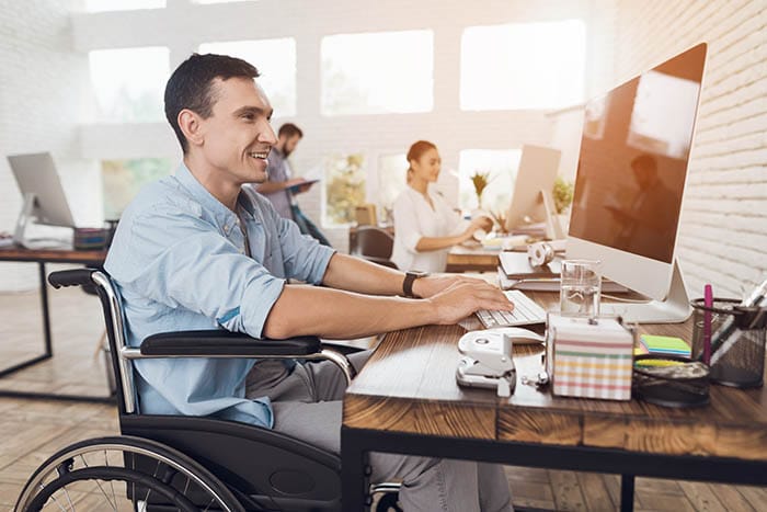 Empleado discapacitado que trabaja en un escritorio en silla de ruedas