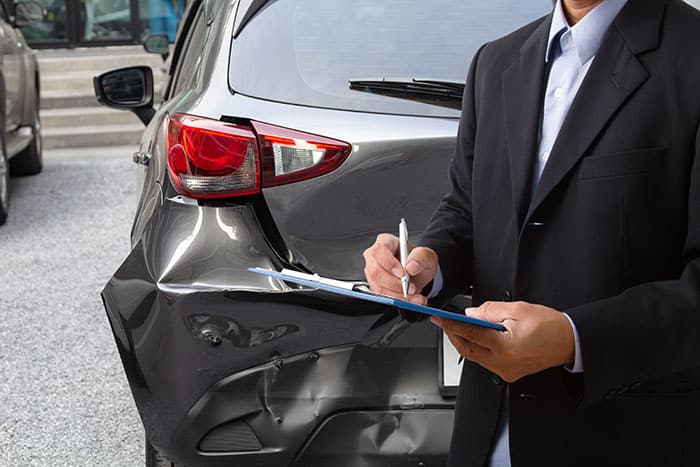 Insurance claims adjuster inspecting car accident damage