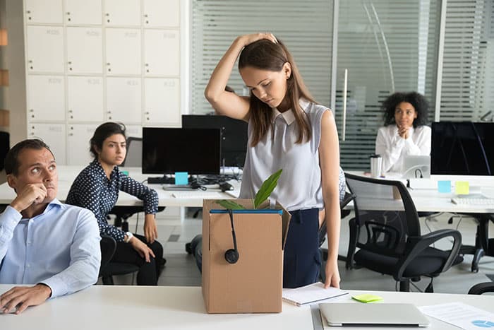 Upset female employee looking at box with belongings