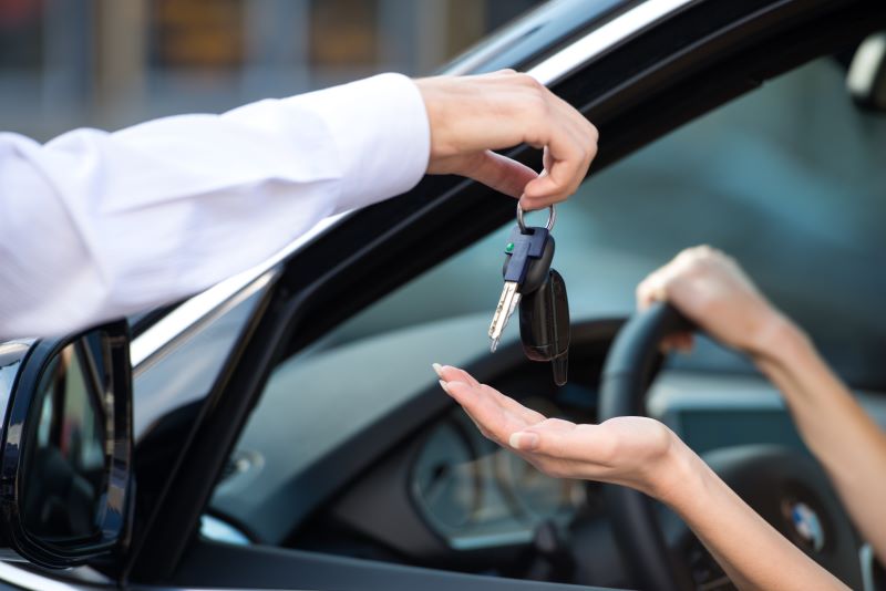 Man handing woman keys to rental car
