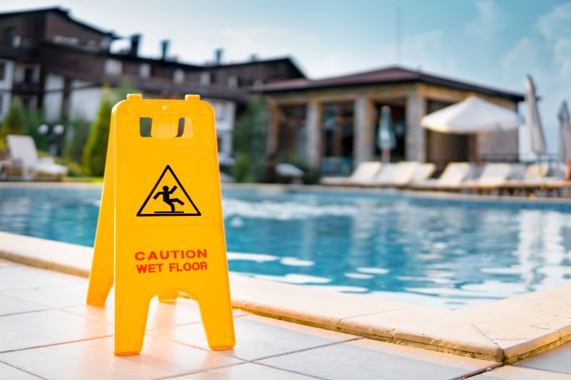 Caution wet floor sign in front of hotel swimming pool