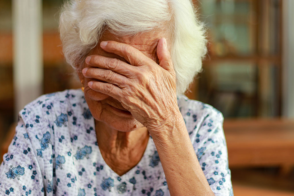 Elderly woman holds hands over face after financial abuse