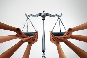 many different races of hands holding the balance scales of justice