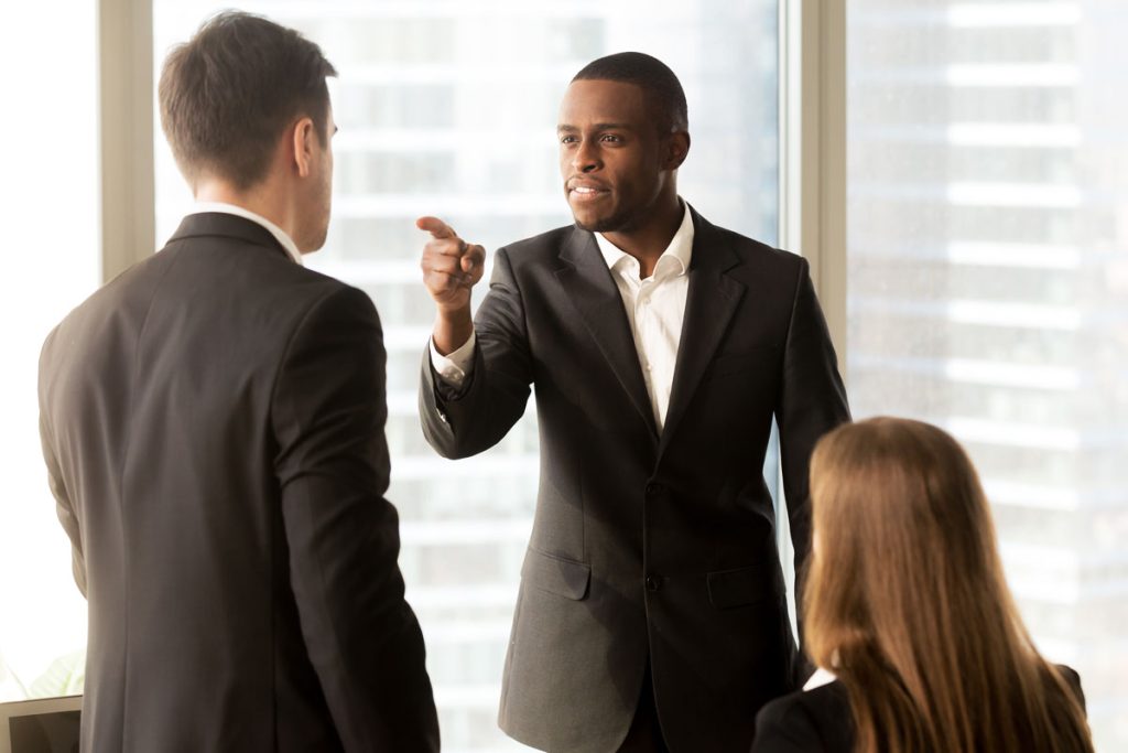 three people in a discussion with a guy pointing the finger at another person