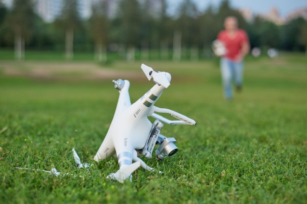 Crashed drone in park. Propeller damage. man running on the background
